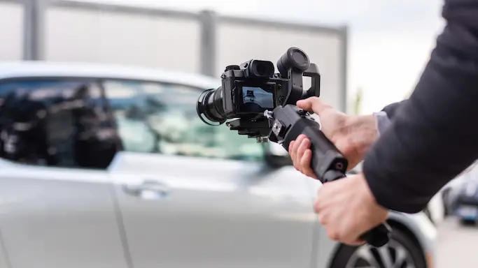 A camera operator filming an exotic car with a gimbal